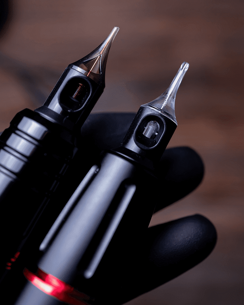 Two close-up fountain pen nibs held by a gloved hand.